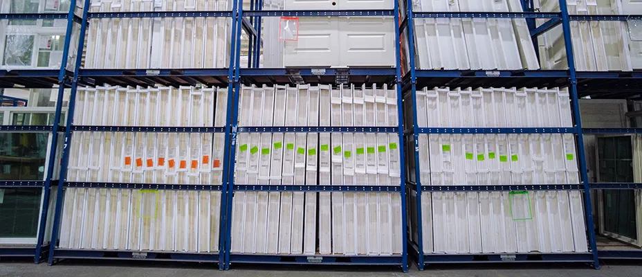 Tall blue racks filled with white interior door slabs in a warehouse